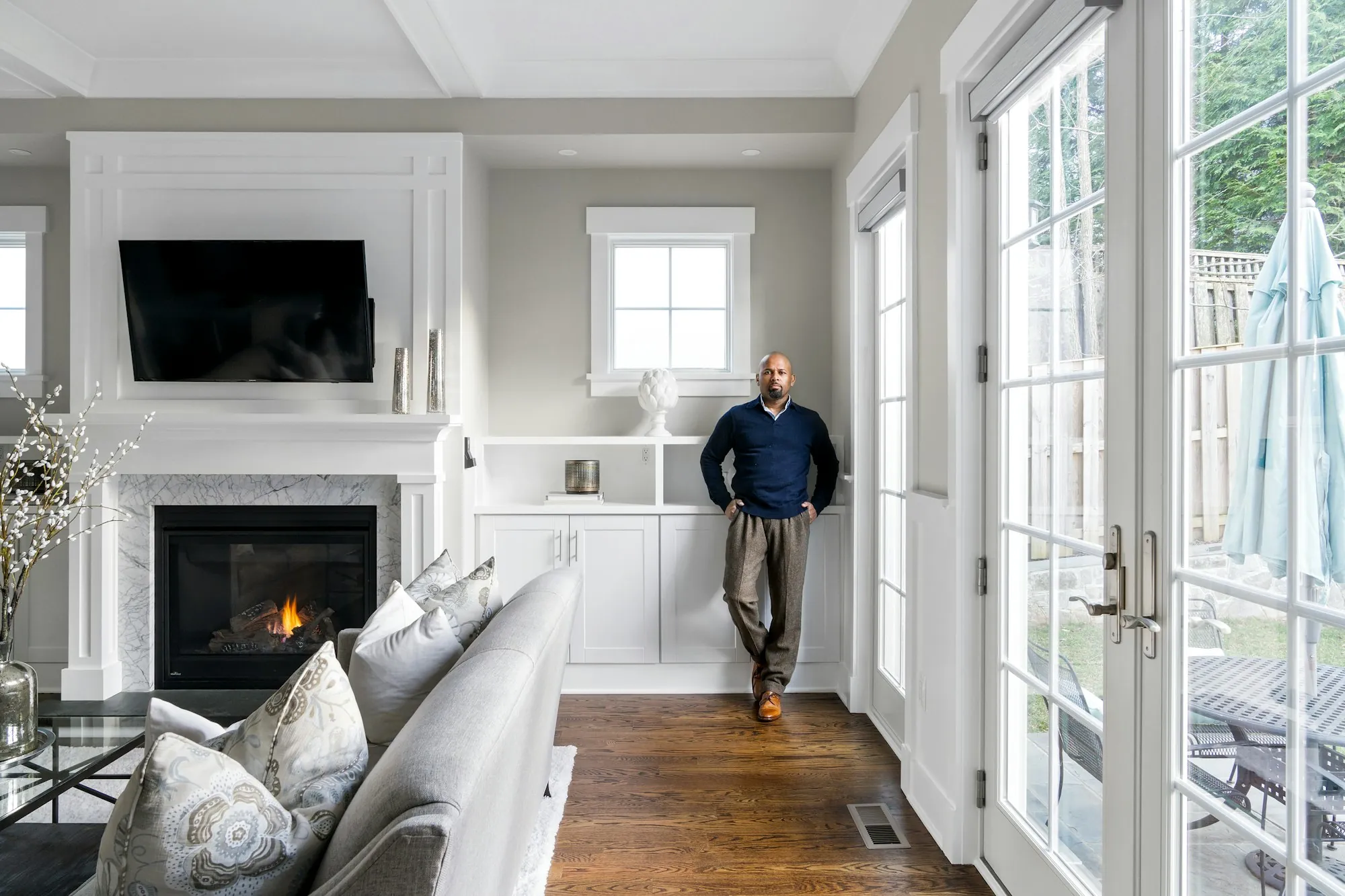 An older man standing at home beside built-in shelves